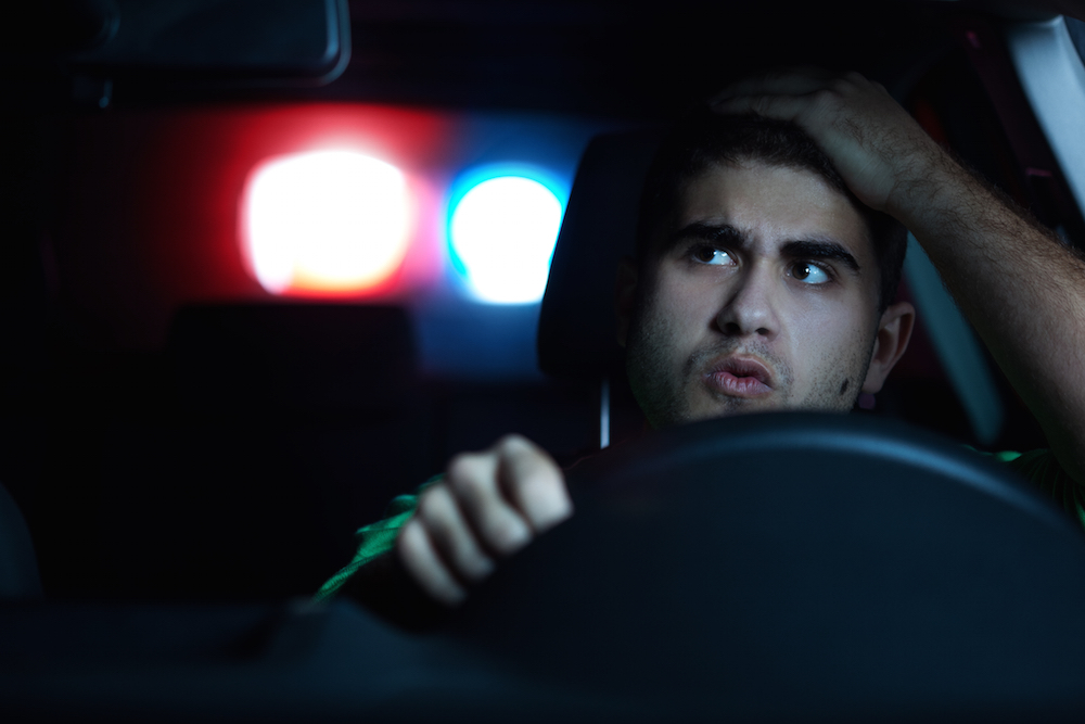 A young man who is being pulled over by a police officer and who will surely need to call the criminal defense lawyers at Hawthorne & Hawthorne.